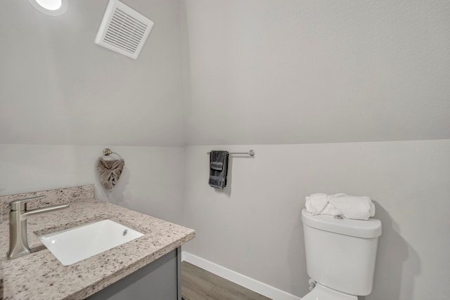 bathroom with vanity, toilet, vaulted ceiling, and hardwood / wood-style floors