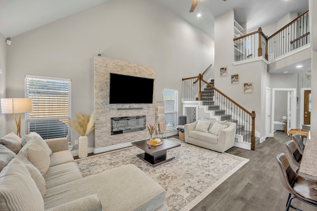 living room with high vaulted ceiling, a wealth of natural light, a fireplace, and hardwood / wood-style floors