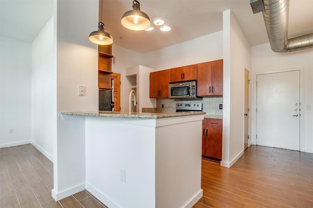 kitchen with stainless steel appliances, decorative backsplash, light wood-type flooring, and kitchen peninsula