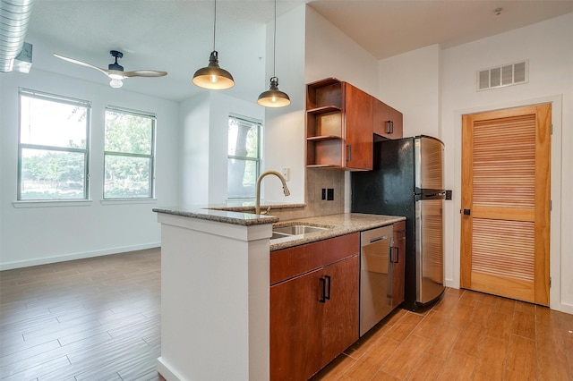 kitchen with pendant lighting, sink, light hardwood / wood-style flooring, appliances with stainless steel finishes, and kitchen peninsula