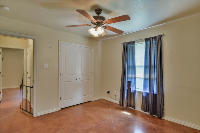 unfurnished bedroom with ceiling fan, a closet, and light tile patterned floors