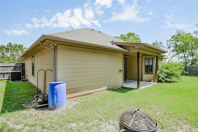 rear view of property featuring a fire pit, a patio area, central air condition unit, and a yard