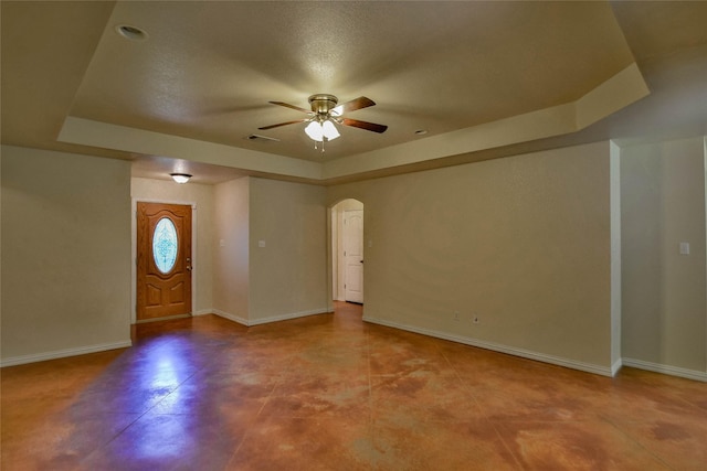 entrance foyer with a tray ceiling, ceiling fan, and a textured ceiling