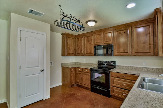 kitchen with black appliances, sink, and dark tile patterned flooring