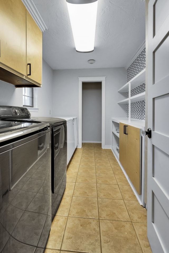 clothes washing area with cabinets, washer and clothes dryer, and light tile patterned floors