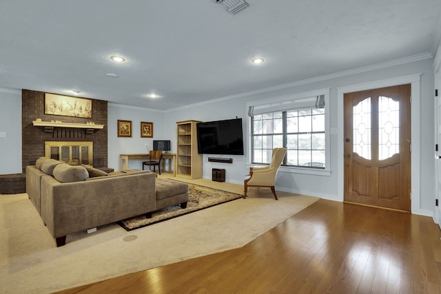 living room featuring crown molding, brick wall, a brick fireplace, and hardwood / wood-style floors