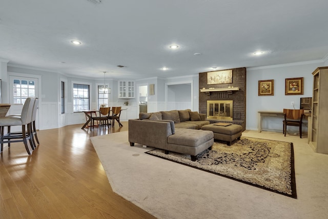 living room featuring a brick fireplace, brick wall, light wood-type flooring, and ornamental molding