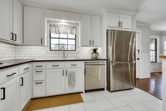 kitchen featuring appliances with stainless steel finishes, white cabinets, backsplash, light tile patterned floors, and crown molding