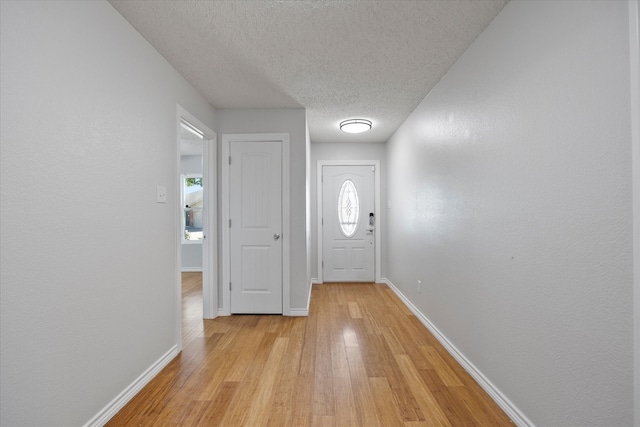 doorway to outside featuring a textured ceiling and light hardwood / wood-style flooring