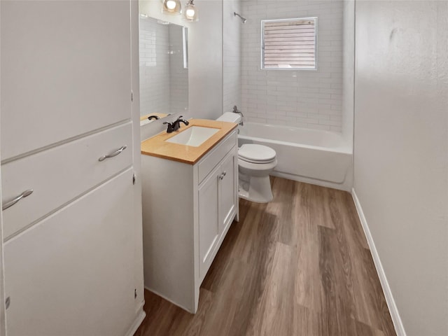 full bathroom with hardwood / wood-style floors, toilet, vanity, and tiled shower / bath