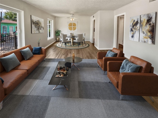 living room with ceiling fan, a textured ceiling, and a wealth of natural light