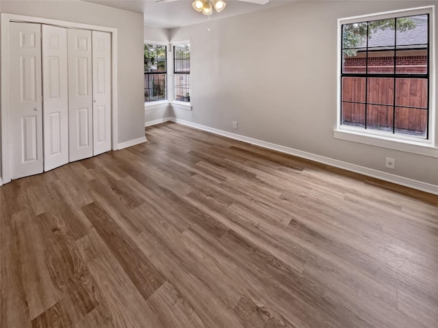 unfurnished bedroom with a closet, light wood-type flooring, ceiling fan, and multiple windows