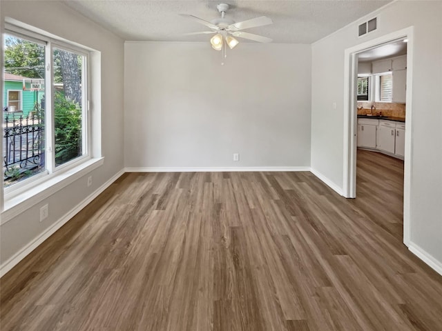 unfurnished room featuring sink, a textured ceiling, ceiling fan, and dark hardwood / wood-style flooring