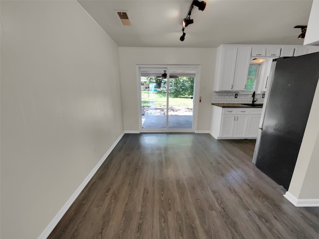 kitchen with white cabinetry, tasteful backsplash, dark hardwood / wood-style floors, and rail lighting