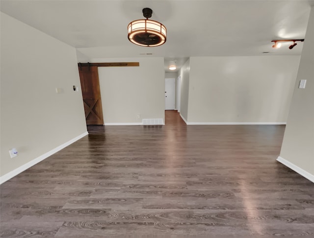 unfurnished room featuring a barn door and dark hardwood / wood-style floors