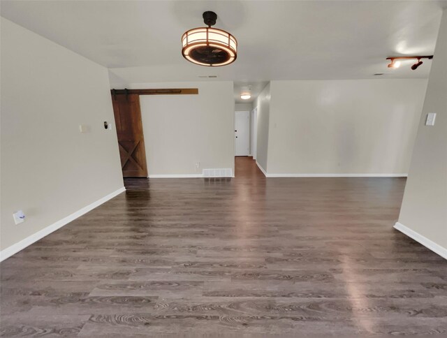 unfurnished living room featuring dark wood-type flooring and a barn door