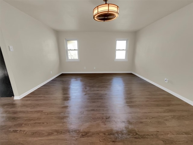 spare room featuring a healthy amount of sunlight and dark hardwood / wood-style flooring