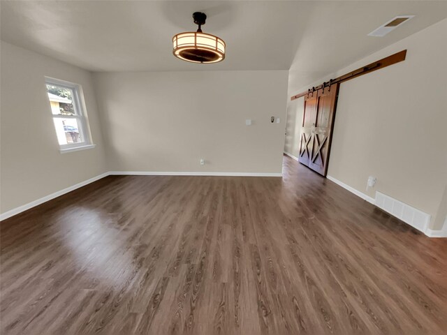 spare room with dark hardwood / wood-style floors and a barn door