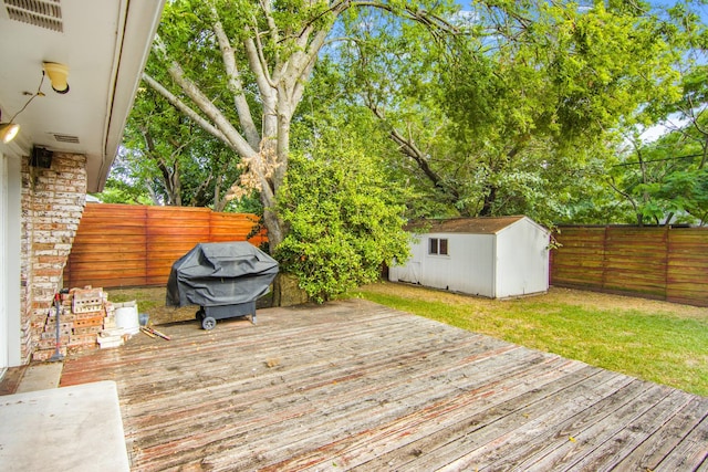 wooden deck featuring a storage unit, an outbuilding, a fenced backyard, and grilling area