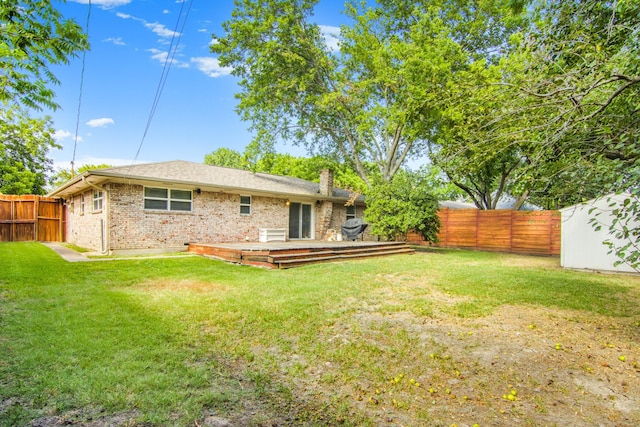 rear view of property featuring brick siding, a lawn, a chimney, and a fenced backyard