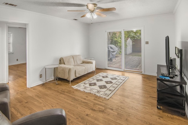 sitting room with visible vents, wood finished floors, and ornamental molding