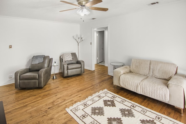 living room featuring wood-type flooring, ceiling fan, and crown molding