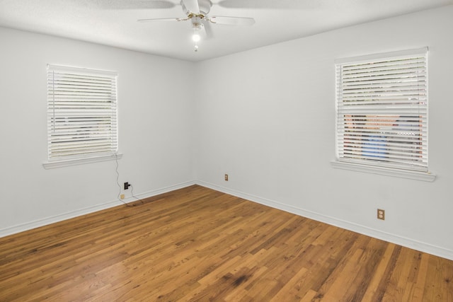 spare room with baseboards, wood finished floors, and a ceiling fan