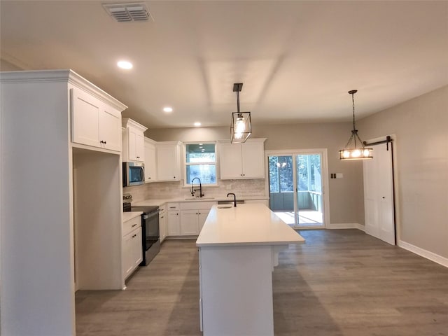 kitchen with pendant lighting, sink, stainless steel appliances, a center island, and white cabinets