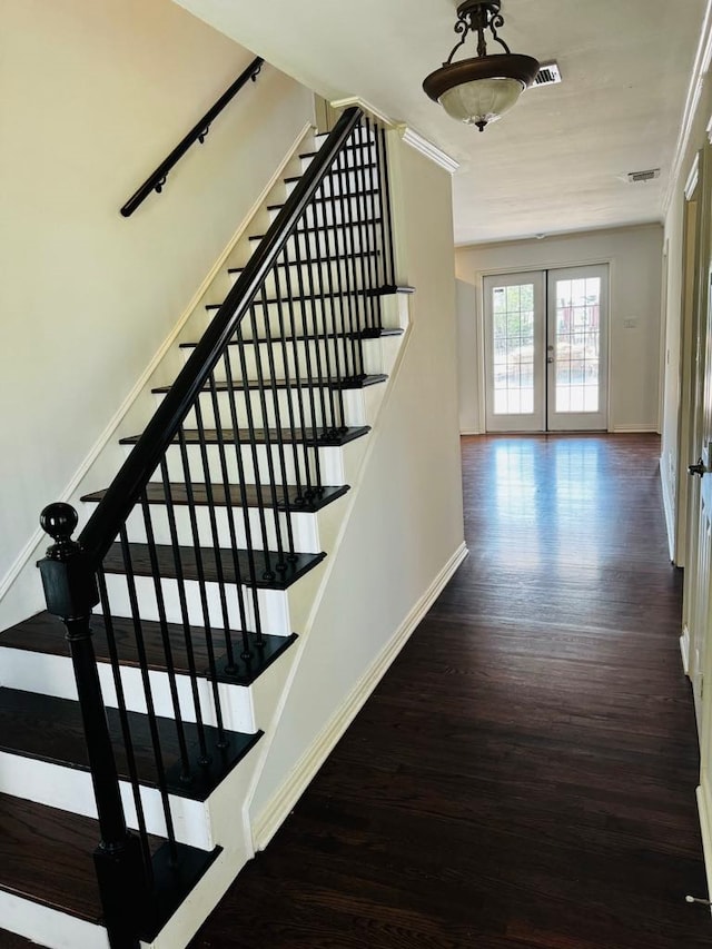 staircase with french doors, hardwood / wood-style floors, and ornamental molding