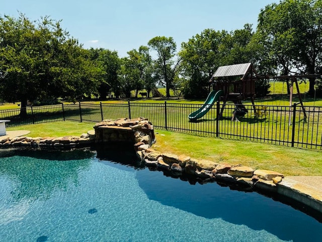 view of swimming pool with a playground and a lawn