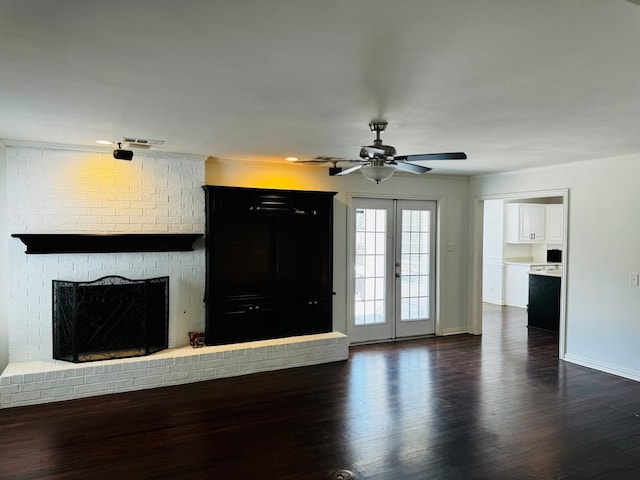 unfurnished living room featuring french doors, dark hardwood / wood-style flooring, a brick fireplace, ornamental molding, and ceiling fan