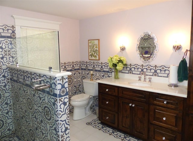 bathroom with tile walls, toilet, vanity, and tile patterned flooring