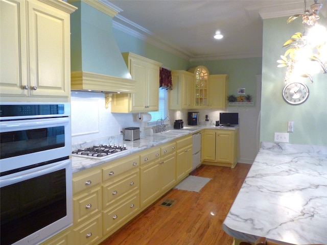 kitchen featuring white appliances, sink, backsplash, ornamental molding, and custom range hood