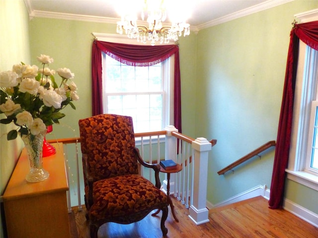 living area featuring an inviting chandelier, ornamental molding, and hardwood / wood-style floors