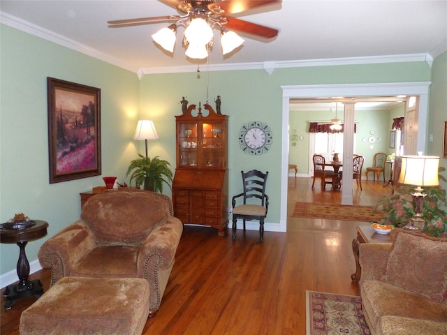 sitting room featuring dark wood-type flooring, ornamental molding, and ceiling fan