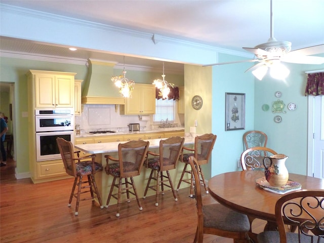 interior space featuring crown molding, custom exhaust hood, cream cabinetry, and white appliances