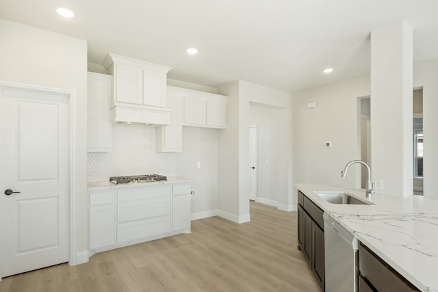 kitchen featuring appliances with stainless steel finishes, white cabinetry, light hardwood / wood-style flooring, sink, and light stone counters