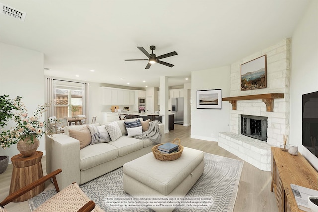 living room featuring a fireplace, light wood-type flooring, and ceiling fan