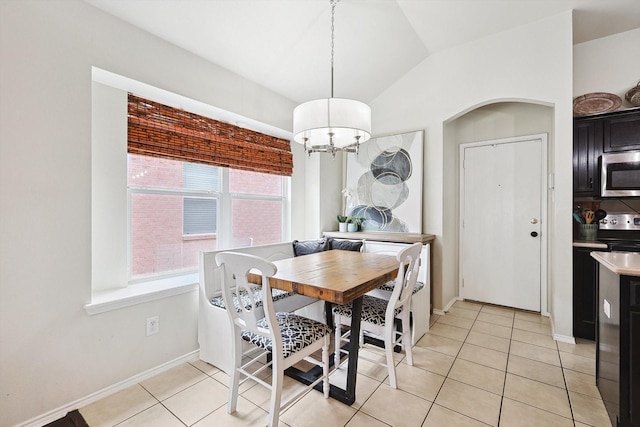 dining space with light tile patterned floors, a notable chandelier, baseboards, and vaulted ceiling