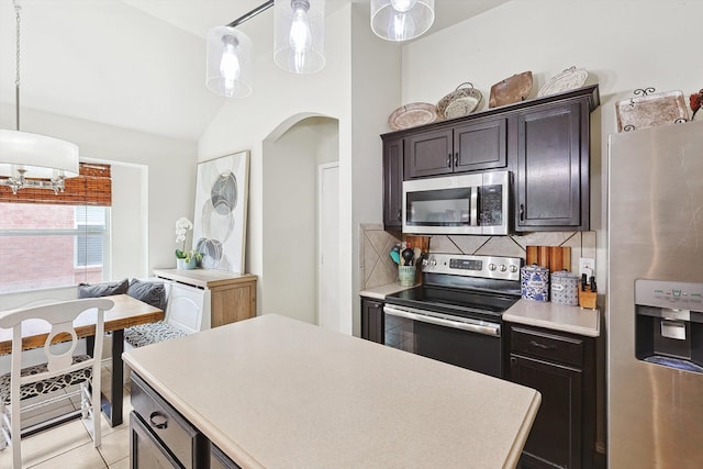 kitchen with tasteful backsplash, decorative light fixtures, light countertops, and appliances with stainless steel finishes