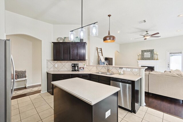 kitchen with light tile patterned flooring, lofted ceiling, sink, appliances with stainless steel finishes, and a kitchen island