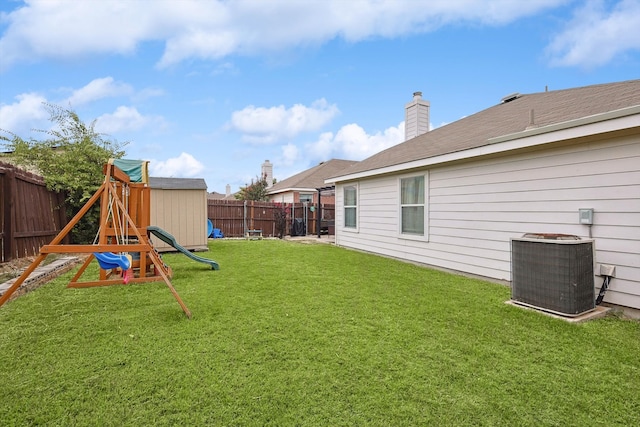 view of yard with central AC unit, a fenced backyard, and a playground