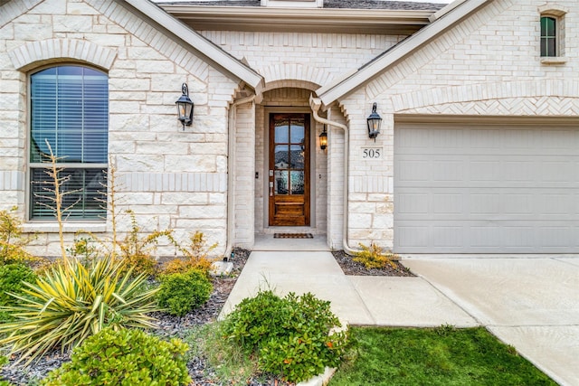 doorway to property with a shingled roof, stone siding, brick siding, and an attached garage