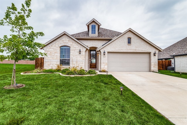 french country home featuring a garage, central AC, and a front lawn