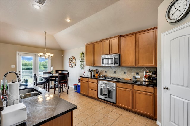 kitchen featuring pendant lighting, vaulted ceiling, decorative backsplash, stainless steel appliances, and a chandelier