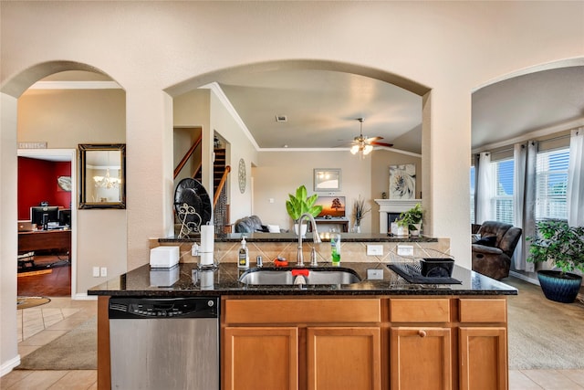 kitchen with dark stone counters, sink, light tile patterned floors, and stainless steel dishwasher