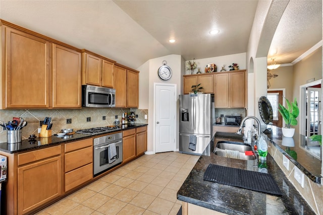 kitchen with lofted ceiling, sink, decorative backsplash, dark stone countertops, and appliances with stainless steel finishes