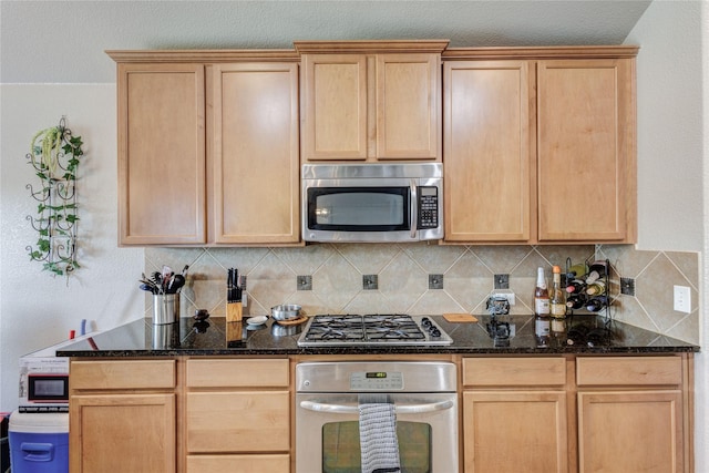 kitchen with decorative backsplash, light brown cabinetry, stainless steel appliances, and dark stone countertops