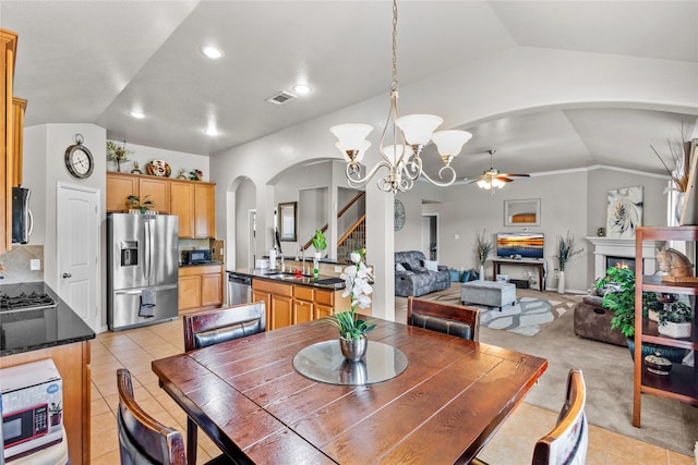 tiled dining area with ceiling fan with notable chandelier, lofted ceiling, and sink