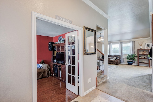 hallway featuring light carpet, a textured ceiling, and ornamental molding